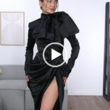 A close-up of Roxxsaurus posing during a Youtube try on haul. Roxi wears a black ruched long sleeve satin gown. She stands in her cream, grey and dark wood tiny home living room.