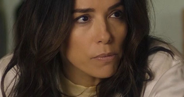 Eva Longoria looks slightly intense. She appears with her long dark brown hair loose and dishevelled. She wears a white dressing gown over a thin tan jumper.