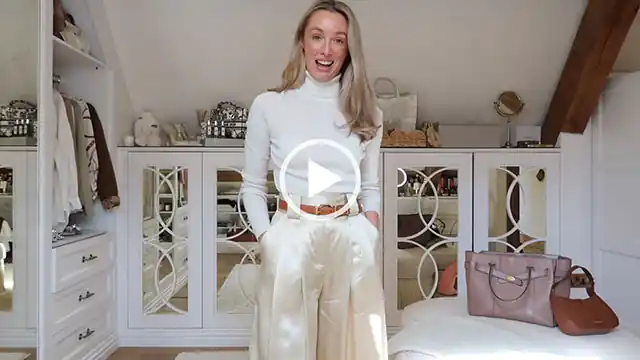 Josie Irons stands in her large dressing room at home. She has both hands in the pockets of the satin style trousers she is wearing. Josie appears in a cream knitted long sleeve top in front of white mirror cabinets and white clothing shelves.