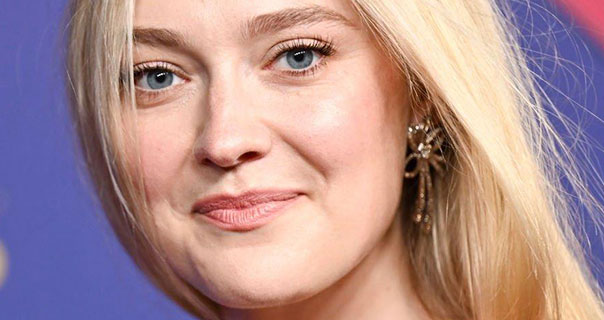 Dakota Fanning is seen with her long blonde hair loose and slightly covering her face. She wears a pair of thin gold flower head earrings and a dark pink lipstick. Dakota appears in front of a mostly blue with bits of gold and red wall.