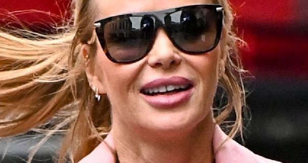 Amanda Holden is seen wearing a large pair of black sunglasses as she walks along a London street. Her blonde hair is tied back in a ponytail and blows in the wind. Amanda appears in a light pink coat, small earrings and a matte lipstick.